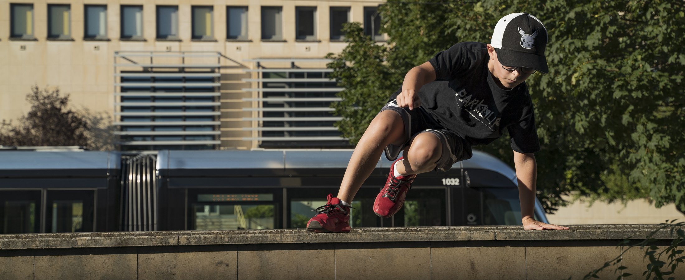 Jeune pratiquant de Parkour en plein mouvement sur un muret
